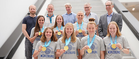 Die Universitätsleitung gratuliert dem Team samt Betreuerstab. Hinten von links zu sehen sind: Andreas Reuter, Leiter des Hochschulsports, Olaf Hoos, wissenschaftlicher Leiter des Sportzentrums, Gernot Haubenthal, Delegationsleiter, und für die Universitätsleitung Kanzler Uwe Klug und Präsident Paul Pauli.